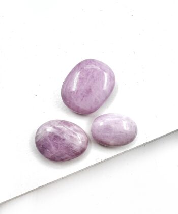 Små lyse lilla ovale glat poleret lommesten krystaller på hvid baggrund