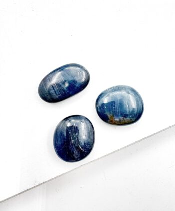 Små mørkeblå ovale glat poleret lommesten krystaller på hvid baggrund