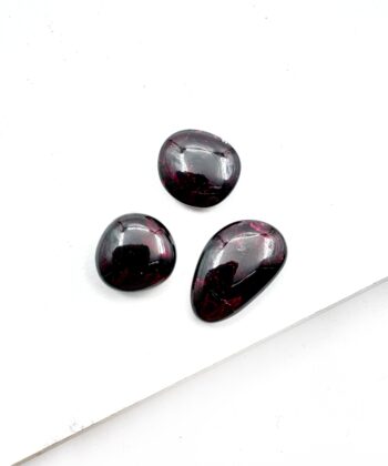 Mørk bordeauxfarvet ovale glat poleret lommesten krystaller på hvid baggrund