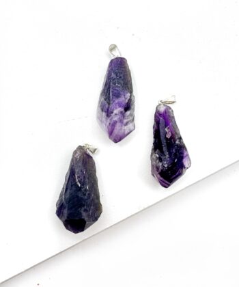 Lilla rå ametyst tænder som vedhæng på hvid baggrund