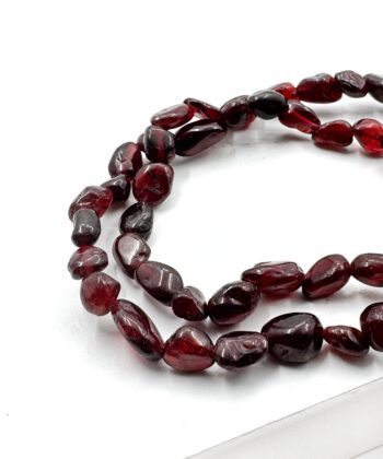 Bordeauxfarvet polerede perle stens armbånd på hvid baggrund