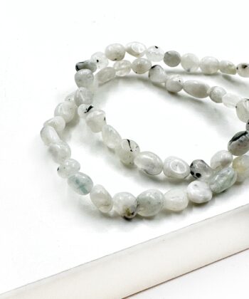 Lys hvid armbånd poleret perler med sorte inklusioner på hvid baggrund