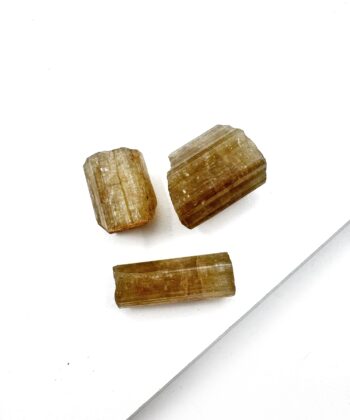 små rå krystaller cylinder i gylden farve på hvid baggrund