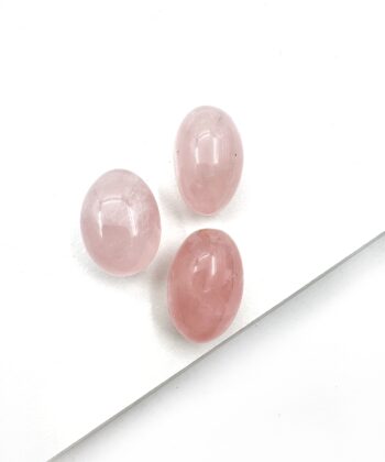 små ovale lyserøde poleret rosenkvarts på hvid baggrund