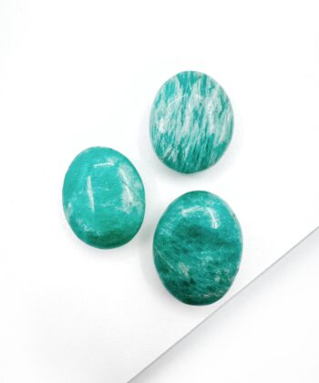 små ovale turkis blålige poleret krystaller på hvid baggrund