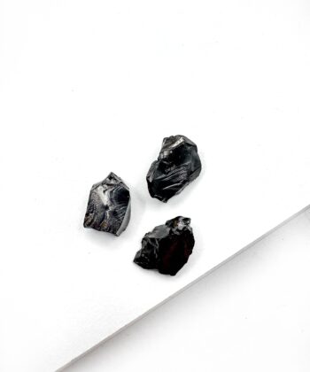 Små sorte rå krystaller på hvid baggrund