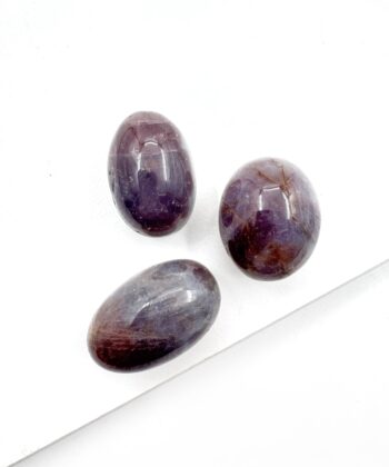 Små ovale lilla poleret krystaller på hvid baggrund