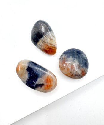 Små ovale multifarvet i blålige og orange farver poleret krystaller på hvid baggrund
