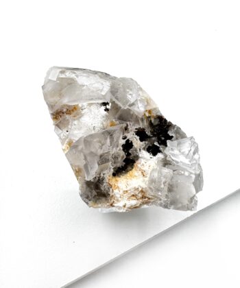 Rå lys hvid krystal med mørke inklusioner inde i på hvid baggrund