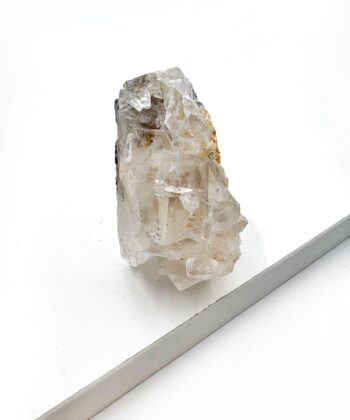 Rå lys hvid krystal med mørke inklusioner inde i på hvid baggrund