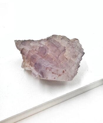 Rå lys lilla krystal med lettere geometriske overflade på hvid baggrund