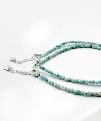 Lyse blå facet armbånd på hvid baggrund.