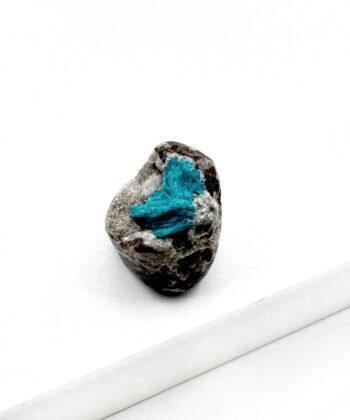 Blå krystal på grå sten med hvid baggrund