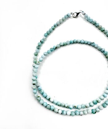 Lyseblå krystaller i halskæde på hvid baggrund