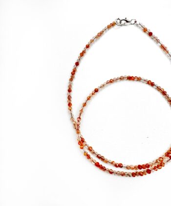 Orange krystaller i halskæde på hvid baggrund