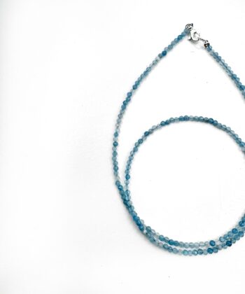 Lyseblå krystaller i halskæde på hvid baggrund