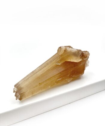 Varm gullig rå krystal sten med parallelle linjer i formen er rustikt kegleformet på hvid baggrund