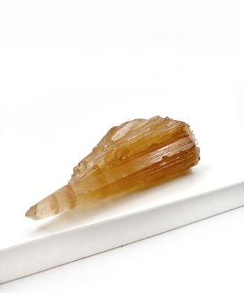 Varm gullig rå krystal sten med parallelle linjer i formen er rustikt kegleformet på hvid baggrund
