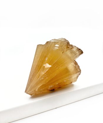 Varm gullig rå krystal sten med parallelle linjer i formen er rustikt kegleformet på hvid baggrund