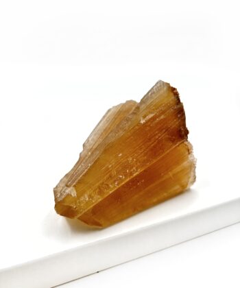 Varm gullig rå krystal sten med parallelle linjer i formen er rustikt kegleformet på hvid baggrund