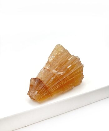 Varm gullig rå krystal sten med parallelle linjer i formen er rustikt kegleformet på hvid baggrund