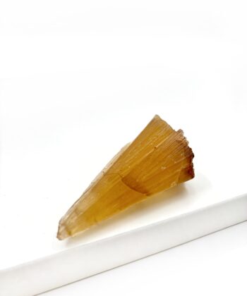 Varm gullig rå krystal sten med parallelle linjer i formen er rustikt kegleformet på hvid baggrund