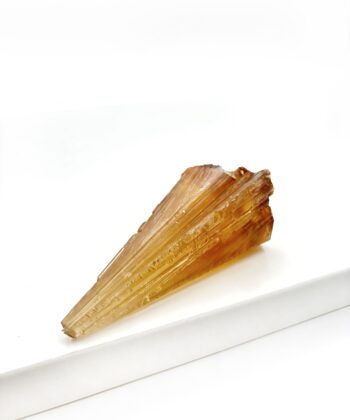 Varm gullig rå krystal sten med parallelle linjer i formen er rustikt kegleformet på hvid baggrund